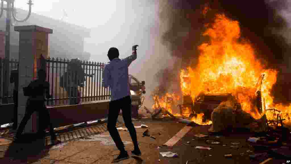 Une voiture brûle devant le bâtiment du parlement au Burkina Faso où des manifestants protestent contre le président Blaise Compaoré, 27 ans au pouvoir, qui cherche à modifier la constitution pour en vue de briguer un autre mandat, à Ouagadougou, au Burkina Faso, le jeudi 30 octobre 2014. (AP Photo / Theo Renaut)