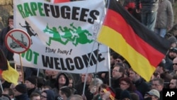 La Droite manifeste avec une banderolle "des réfugiés violeurs" ne sont pas les bienvenus - !Restez chez vous!" et un signe d'une mosquée barrée pendant leur marche a Cologne, Allemagne, samedi le 9 Janvier, 2016. Les femmes activistes de droite , des manifestants d'extrême-droite et de gauche, les contre- manifestants, sont tous descendus dans les rues de Cologne le samedi à la suite d'une vague de vols et d'agressions sexuelles du Nouvel An à Cologne blâmé en grande partie sur les étrangers . ( AP Photo / Juergen Schwarz )