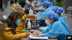 北京一位女子正在醫務人員的指導下填寫個人信息準備接種新冠病毒疫苗。（2021年1月15日）