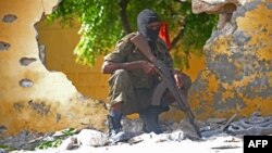 FILE - A Somali soldier stands guard next to the site where al-Shabab militants carried out a suicide attack against a military intelligence base in Mogadishu, June 21, 2015.