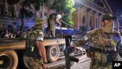 瓦格納僱傭軍士兵在俄羅斯羅斯托夫的街道上往一輛拖運車上裝載坦克。(2023年6月24日)