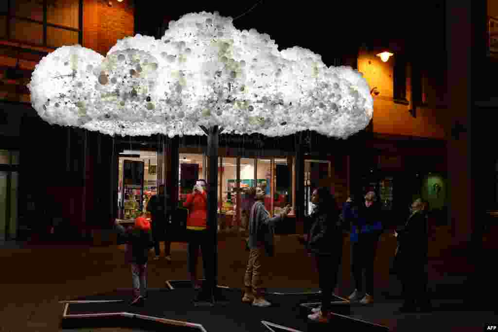 Visitors admire the artwork 'Cloud', formed from 6,000 incandescent light bulbs, during a rehearsal for 'Lumiere Durham' light festival in Durham, northeast England, Nov. 13, 2019.