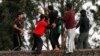 FILE - In this Sept. 21, 2010 file photo, asylum seekers stop a fellow detainee from jumping off the Villawood Detention Center roof in Sydney, Australia, during a protest by the detainees who say they are scared of being returned to their home countries 
