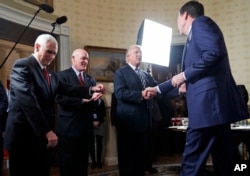 FILE - President Donald Trump (2-L) shakes hands with then-FBI Director James Comey (R) in the Blue Room of the White House in Washington, Jan. 22, 2017. Part of special counsel Robert Mueller's investigation into Russia's meddling focuses on whether Trump obstructed justice by firing Comey, who at he time was overseeing the probe.