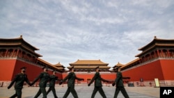 Soldiers wearing protective face masks march past the closed entrance gates to the Forbidden City, usually crowded with tourists before the new coronavirus outbreak in Beijing, Thursday, March 12, 2020. For most people, the new coronavirus causes…