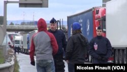 Des policiers s'adressent à des migrants près du camp de Calais. (Nicolas Pinault/VOA)