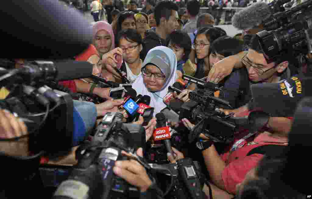 A family member of passengers aboard a missing Malaysia Airlines plane is mobbed by journalists at Kuala Lumpur International Airport in Sepang, outside Kuala Lumpur.