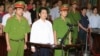 លោក Cu Huy Ha Vu (C) ឈរ​​នៅ​​ចន្លោះ​​ប៉ូលិស​ពីរនាក់​ក្នុង​ពេល​ជំនុំ​ជម្រះ​រឿង​ក្តី​របស់​លោក​នៅ​ក្នុង​តុលាការ​មួយ​ក្នុង​ទីក្រុង​ហាណូយ​នៃ​ប្រទេស​វៀតណាម កាលពីថ្ងៃទី២១ ​ខែសីហា ឆ្នាំ២០១១។