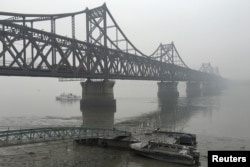 FILE - Trucks move across the bridge linking North Korea with the Chinese border city of Dandong, March 3, 2016. Nearly 90 percent of all North Korean trade flows across its border with China.
