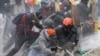Los manifestantes antigubernamentales se protegen de un cañón de agua de la policía durante los enfrentamientos en Madrid, en las afueras de Bogotá, el viernes 28 de mayo de 2021.