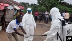 Les agents de santé se lavent les mains après avoir pris un échantillon de sang d'un enfant pour tester le virus Ebola à la périphérie de Monrovia, au Libéria. 