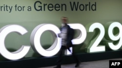 Un participant à la COP29 passe devant un logo lors de la Conférence des Nations Unies sur le changement climatique à Bakou, en Azerbaïdjan, 21 novembre 2024. AFP