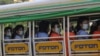Factory workers wearing protective face masks and shields ride a truck as they go to their works in Hlaing Tharyar Industrial Zone Monday, Oct. 12, 2020, on the outskirts of Yangon, Myanmar. Myanmar government allowed Monday to resume Cut-Make-Pack …