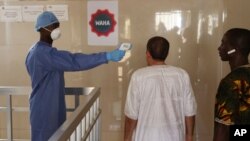 Un agent de santé, à gauche, prend la température des quelques personnes à l'hôpital gouvernemental Ignace Deen à Conakry, en Guinée, 18 mars 2016.
