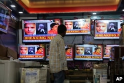 FILE - An Indian boy watches as television channels show news about International Court of Justice hearing the case of Indian naval officer Kulbhushan Jadhav at a shop in Jammu, India, May 15, 2017.