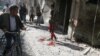 People inspect the damage as a civilian walks near blood stains at a market hit by air strikes in Aleppo's rebel-held al-Fardous district, Syria, Oct. 12, 2016. 
