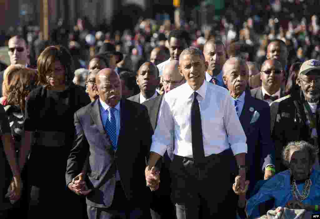 អតីតប្រធានាធិបតីលោក Barack Obama (ស្ដាំ) កាន់ដៃលោក John Lewis (ឆ្វេង) ដើរឆ្លងកាត់ស្ពាន Edmund Pettus Bridge ដើម្បីប្រារព្ធខួបទី ៥០ នៃការទាមទារសិទ្ធិពលរដ្ឋ នៅក្រុង Selma រដ្ឋ Alabama ថ្ងៃទី ៧ ខែមីនា ឆ្នាំ២០១៥។ 