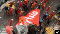 Rescuers wave at an Indonesian Air Force helicopter near portion of AirAsia Flight 8501 after it was recovered from the sea floor on the deck of a rescue ship on the Java Sea, Saturday, Jan. 10, 2015.