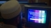 FILE - A Pakistani viewer looks at a television screen flashing suspension notice of GEO News channel in Islamabad, Pakistan.