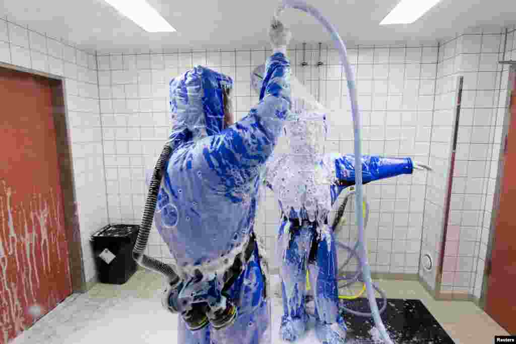Docteur en médecine tropicale, Florian Steiner (G) nettoie la salle du médecin Thomas Klotzkowski dans une chambre de désinfection à la station de quarantaine pour les patients atteints de maladies infectieuses à l'hôpital de la Charité à Berlin, le 11 Août 2014. REUTERS / Thomas