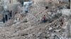 A civilian collects tree branches amid the rubble of a damaged site in the rebel-held besieged Qadi Askar neighborhood of Aleppo, Syria, Nov. 24, 2016. 