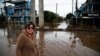 FILE - Orioplina Bechiln, a street barbecue vendor, walks along a flooded street around the Arena do Gremio stadium in Porto Alegre, Rio Grande do Sul State, Brazil, on May 29, 2024.