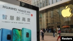2018年10月26日在中國上海的Apple商店外面，顧客排隊購買新的iPhone XR手機，附近有華為Mate 20系列產品的廣告。