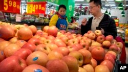 2018年3月23日，在北京一家超市，一位身穿帶有美國食品公司標誌的制服的女子幫助一位顧客購買蘋果。