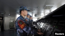 FILE - Chinese naval soldiers are pictured manning their stations on China's first aircraft carrier Liaoning, as it travels towards a military base in Sanya, Hainan province.