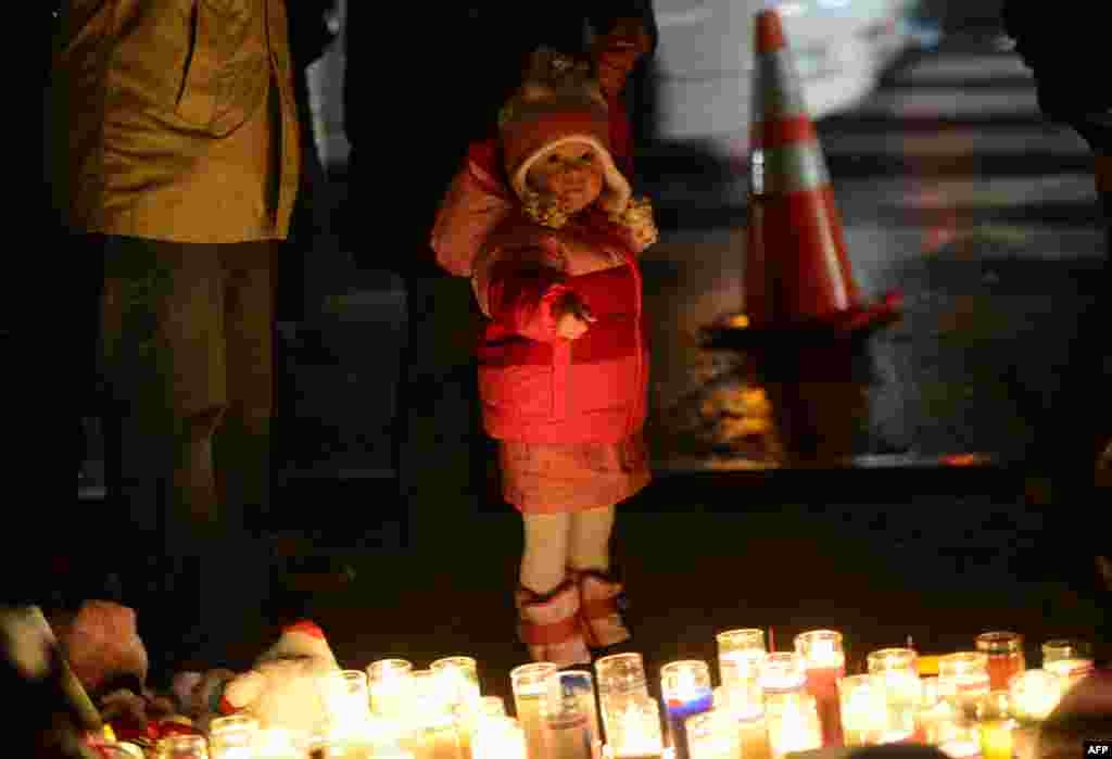 Un petit enfant observant des cierges déposés à un mémorial dédié aux victimes du massacre de l'école primaire Sandy Hook
