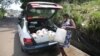 Une femme charge dans un taxi des conteneurs remplis d'eau recueillie dans une source naturelle à Libreville, au Gabon, le 2 février 2021.