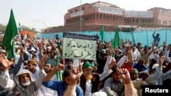 Un partisan de Tehreek-e-Labaik Pakistan, un parti politique islamiste, porte un signe où l’on peut lire en urdu « enlever Zahid Hamid » pendant le sit-in le long de la route principale à Karachi. 27 novembre 2017
