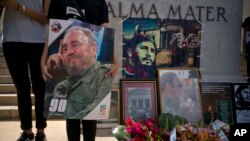 Quelques personnes tiennent des images de Fidel Castro lors d’un regroupement spontané après l’annonce de la mort du leader historique cubain à La Havane, Cuba, 26 novembre 2016. 