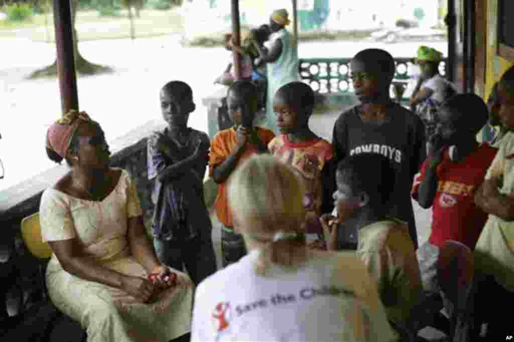 Carolyn Miles, au premier plan, présidente et chef de la direction de Save the Children, discutent avec des orphelins dans la ville d’Unification, Libéria, à quelques 40 km (25 miles) de la capitale Monrovia, vendredi le 3 octobre 2014.