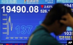 一位香港市民行經股市指數報告版前
