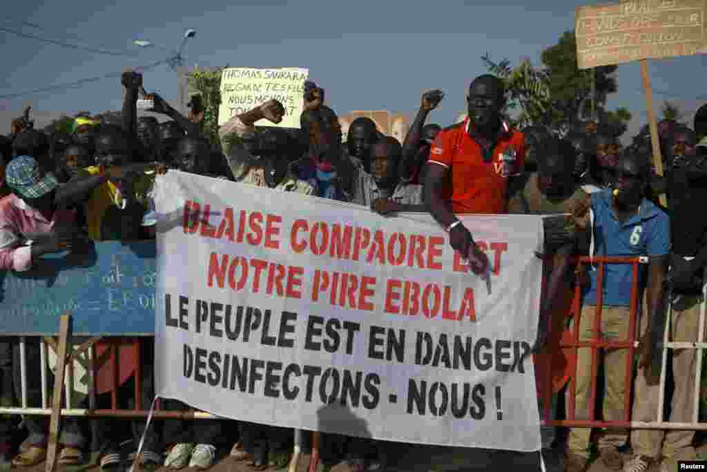 Des manifestants tiennent avec une banderole avec la mention “Balise Compaoré est notre Ebola : Le peuple est en danger, désinfectons-nous !» à Ouagadougou, Burkina Faso, le 20 octobre 2014. La police a lancé des grenades à gaz lacrymogène aux manifestants qui ont usé des pierres à la fin d’une manifestation qui avait regroupé des dizaines de milliers de gens. REUTERS/Joe Penney