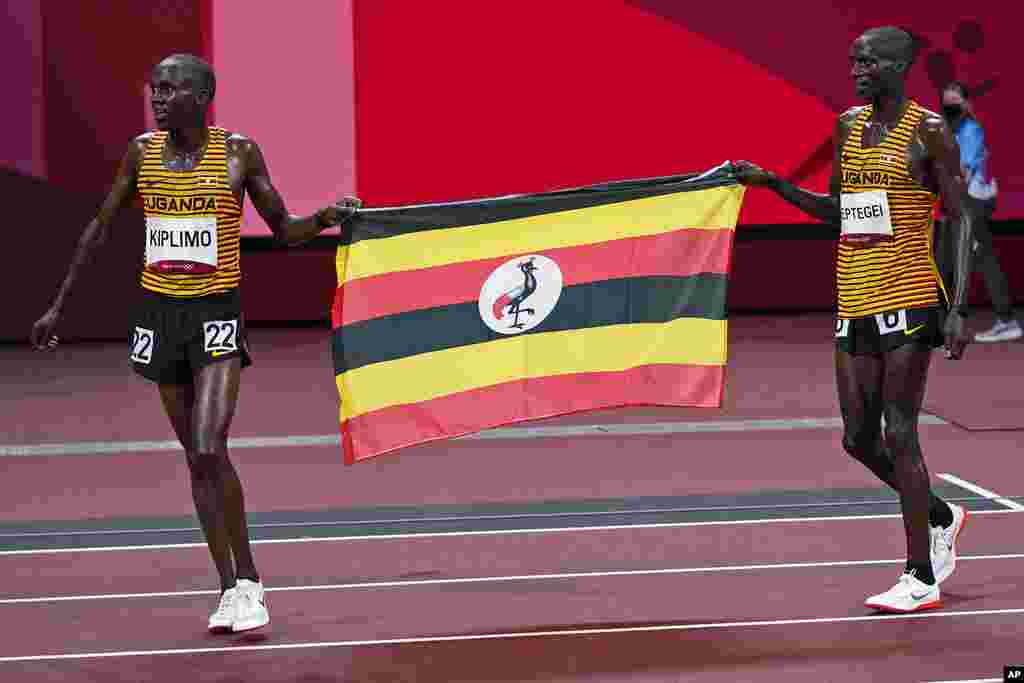 Second placed Joshua Cheptegei, left, of Uganda, and third placed teammate Jacob Kiplimo celebrate with their national flag after the runs in the men's 10,000-meters final at the 2020 Summer Olympics, Friday, July 30, 2021, in Tokyo. (AP Photo/David J. Phillip)