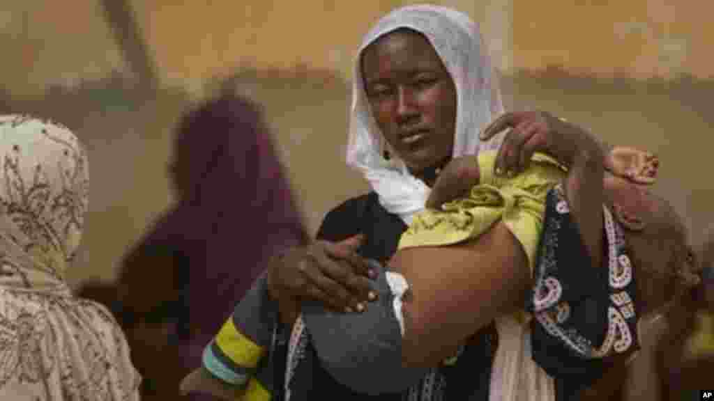 Halime Moussa, 3, reçoit un traitement par un tube d'alimentation nasal et avec les mains bandées pour l'empêcher de retirer, à la salle de nutrition thérapeutique de l'hôpital de la ville, dont sa mère Kaltouma Abakar, à gauche, a voyagé 70 km pour atteindre, à Mao, capitale de la région du Kanem au Tchad, le mardi 17 Avril 2012. (AP Photo / Ben Curtis)