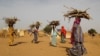 FILE - Women carry fire woods at the Boudouri site for displaced persons outside the town of Diffa in southeastern Niger, June 21, 2016. 