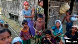 FILE - Rohingya Muslims pass time near their shelter at a refugee camp outside Sittwe, Myanmar, June 2014.