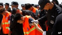 Chinese, in an orange vest, arrested over an alleged internet scam, are escorted by Chinese police officers before boarding at Phnom Penh International Airport, in Phnom Penh, Cambodia, Thursday, Oct. 12, 2017.