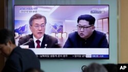 FILE - People watch a TV screen showing file footage of South Korean President Moon Jae-in and North Korean leader Kim Jong Un during a news program ahead of the inter-Korean summit at the Seoul Railway Station in Seoul, South Korea, April 26, 2018. 