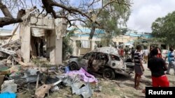 Des civils et une voiture détruite sur les lieux d’une explosion dans le district de Hodan, à Mogadiscio, en Somalie, le 10 septembre 2018.