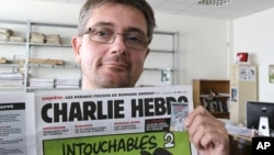 Stéphane Charbonnier aussi alias Charb, directeur de publication de l'hebdomadaire satyrique Charlie Hebdo, affiche la Une du journal, alors qu'il pose pour les photographes à Paris. (AP Photo / Michel Euler, Archives).