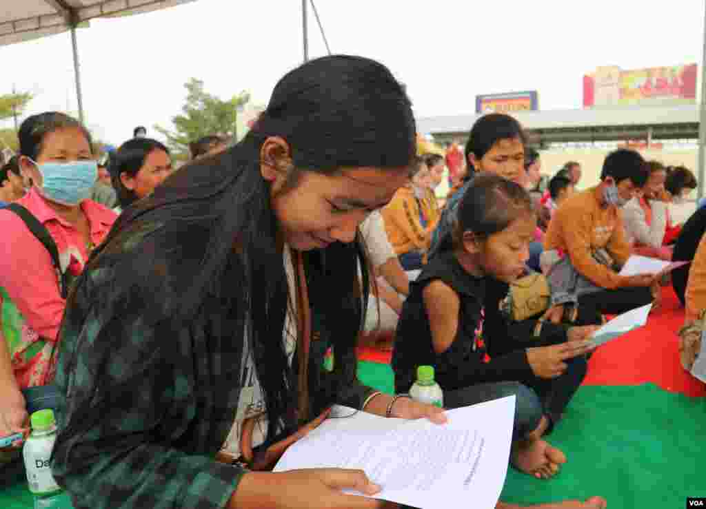 A young woman reads an event note, as she attends the 109th International Women Rights Day at Freedom Park, in Phnom Penh, March 8, 2020. (Kann Vicheika/VOA Khmer)