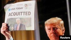 Le président américain Donald Trump brandit une copie de la première page du quotidien USA Today montrant des nouvelles de son acquittement, à Washington, aux États-Unis, le 6 février 2020. 