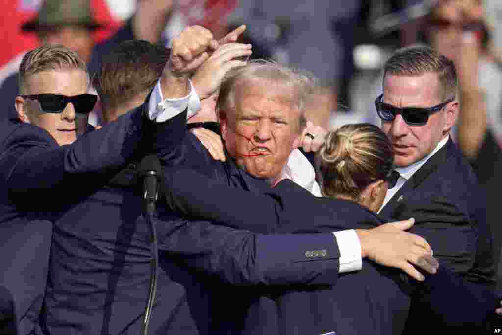 Les services secrets évacuent l'ancien président Donald Trump de la scène. Le candidat républicain brandit son poing.