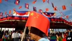 រូបឯកសារ៖​ ស្ត្រីខ្មែរម្នាក់កាន់ទង់ជាតិចិន នៅក្នុងពិធីសម្ពោធស្ពានមិត្តភាពកម្ពុជា-ចិន នៅខេត្តកណ្តាល កាលពីថ្ងៃទី៣ ខែសីហា ឆ្នាំ២០១៥។