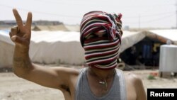 Penaberekî Kurd yê Sûrî li kampeke penaberan ya li bajarê Zaxoyê nîşana serkeftinê dike. Hezîran 23, 2012. 