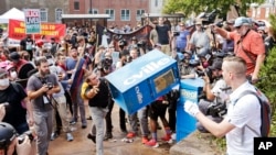 Accrochages entre des nationalistes blancs (à droite) et un manifestant antiraciste (jetant la boîte à journaux), Charlottesville, Virginie, le 8 août 2017.